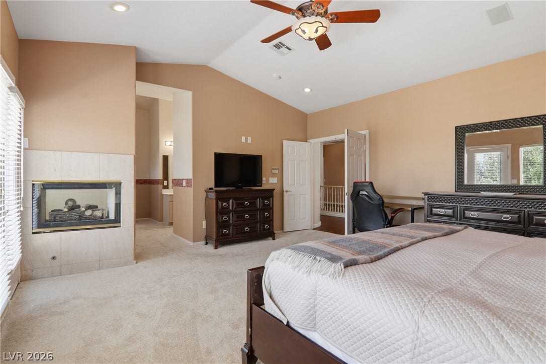 2218 Alanhurst Drive, Henderson, NV 89052 Relax in this primary bedroom featuring a cozy fireplace and a ceiling fan for optimal comfort.