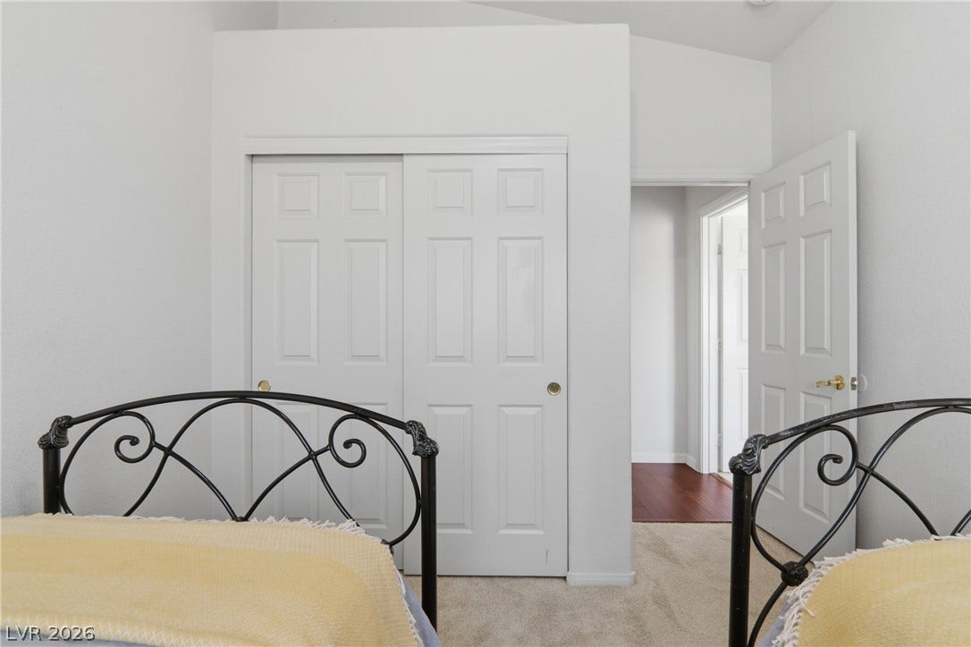 2218 Alanhurst Drive, Henderson, NV 89052 Well-lit bedroom features durable carpeting, a convenient closet, and easy access to an adjoining space with hardwood flooring.