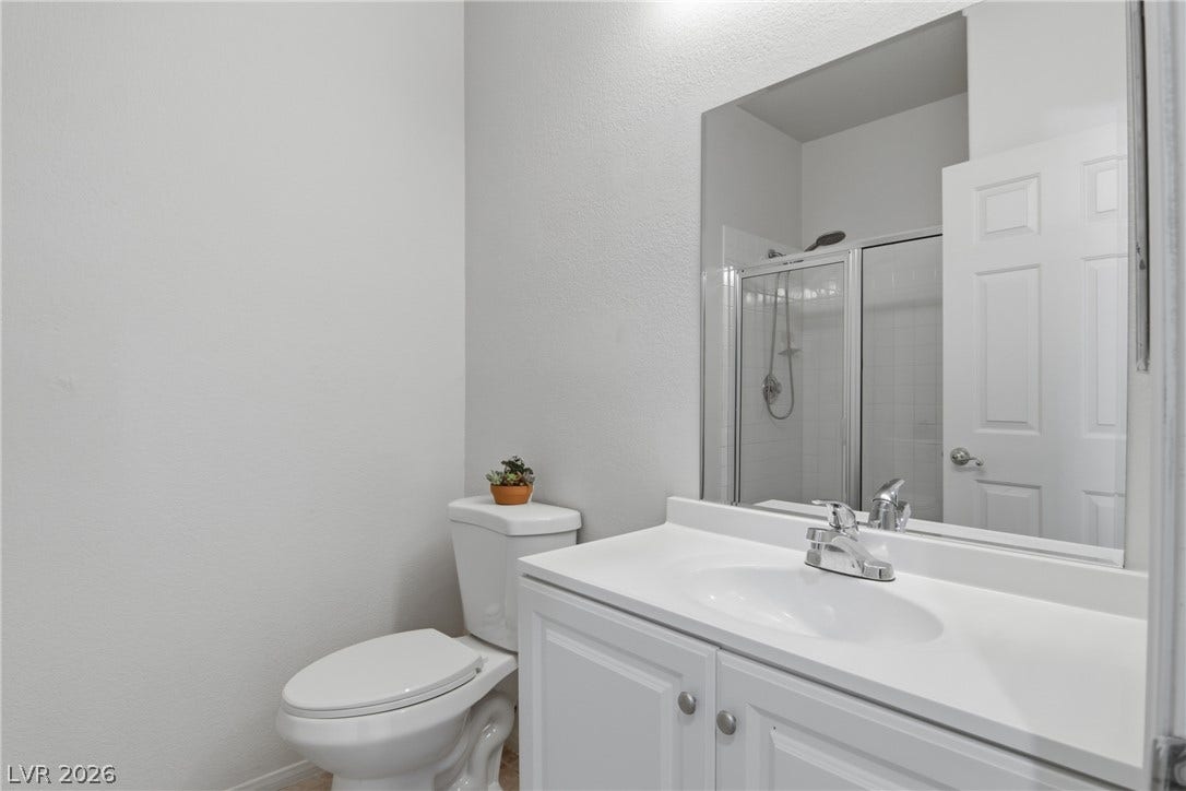 2218 Alanhurst Drive, Henderson, NV 89052 A well-appointed bathroom features a single vanity, a toilet, and a glass-enclosed shower.