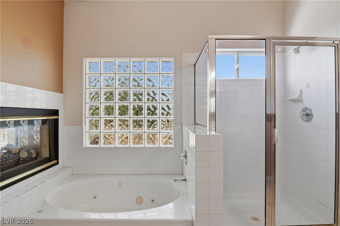 2218 Alanhurst Drive, Henderson, NV 89052 Relax in the primary bath's soaking tub next to a cozy fireplace and glass block window.