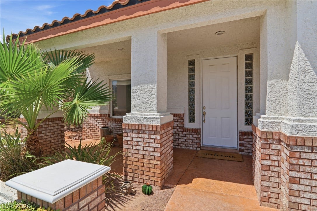 2218 Alanhurst Drive, Henderson, NV 89052 A welcoming brick and stucco facade greets visitors with desert landscaping and a tiled entry.