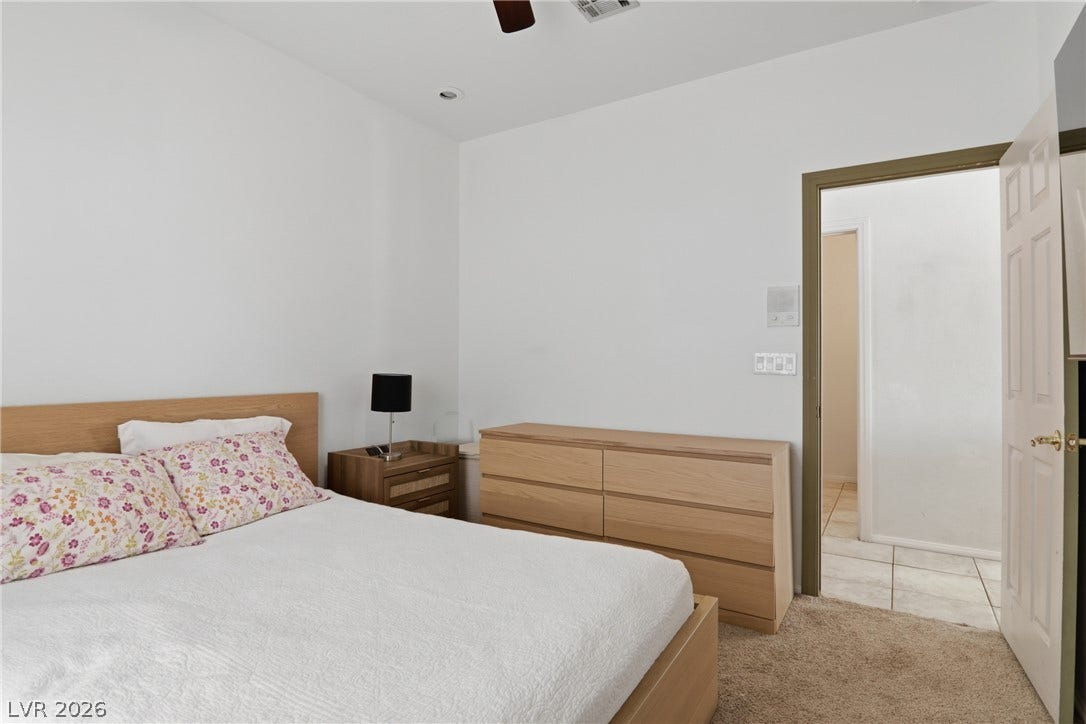 2218 Alanhurst Drive, Henderson, NV 89052 A well-lit primary bedroom offers plush carpeting and a convenient open doorway to an adjacent space.