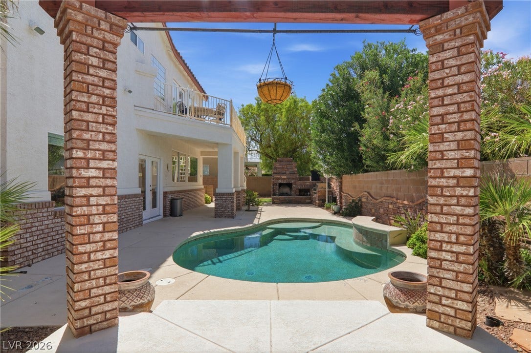 2218 Alanhurst Drive, Henderson, NV 89052 An inviting backyard oasis offers a sparkling pool and a built-in outdoor fireplace for memorable gatherings.