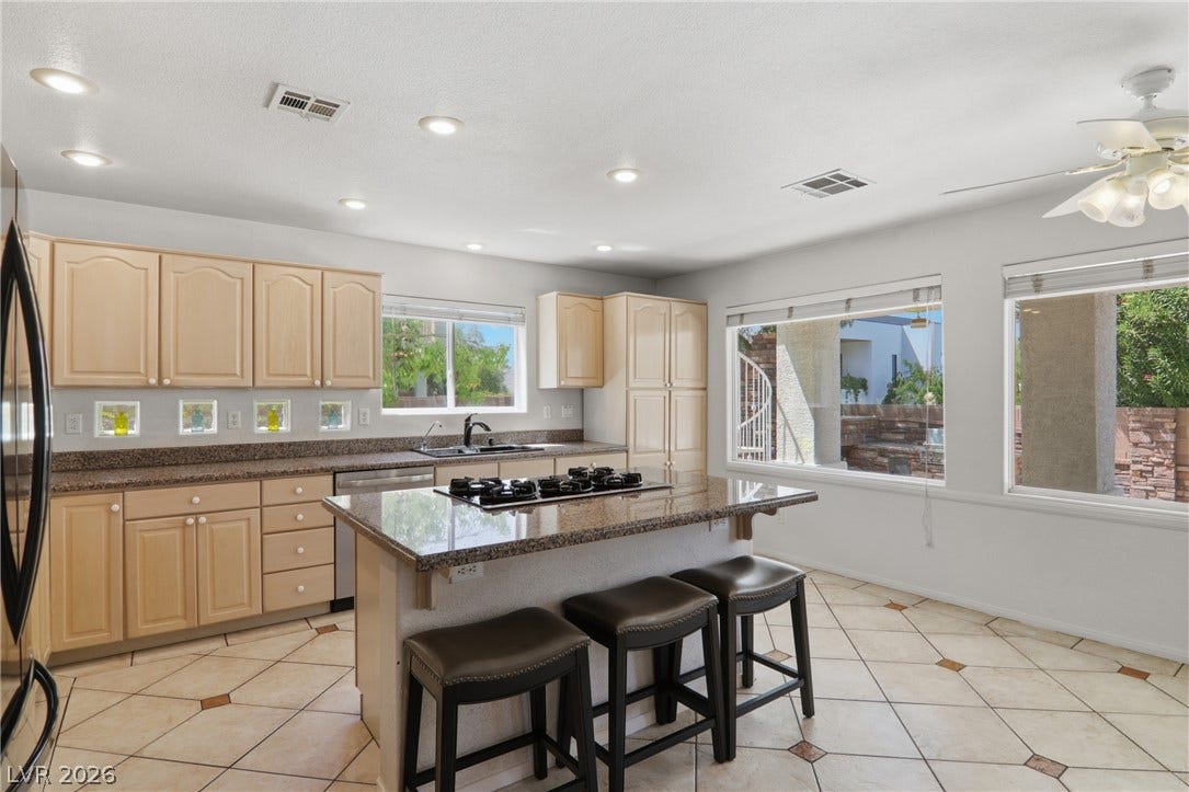 2218 Alanhurst Drive, Henderson, NV 89052 A well-lit kitchen with granite countertops, stainless steel appliances, and a central island with bar seating.
