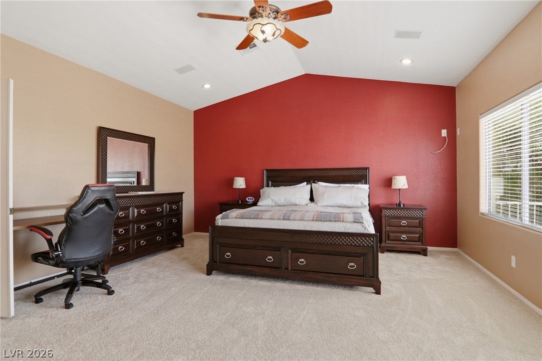 2218 Alanhurst Drive, Henderson, NV 89052 An inviting bedroom features a vaulted ceiling, soft carpeting, and a window with blinds, creating a comfortable living space.