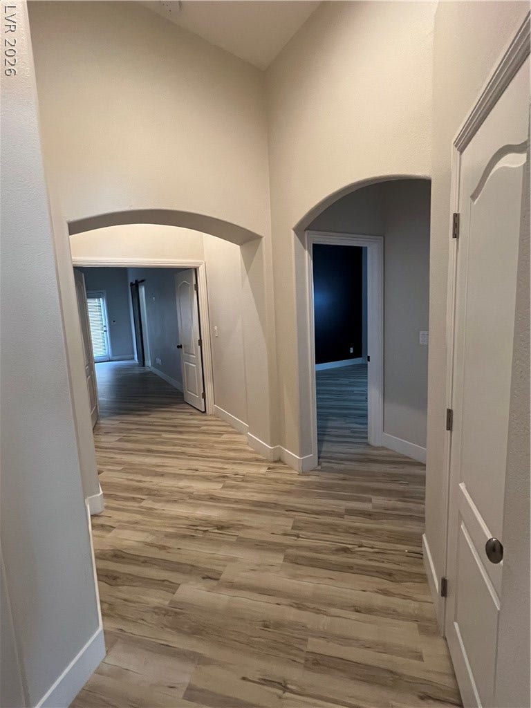 9621 Dancing Pond Way, Las Vegas, NV 89178 Long, flowing wood-look flooring stretches through this well-lit interior hallway, creating a seamless path.