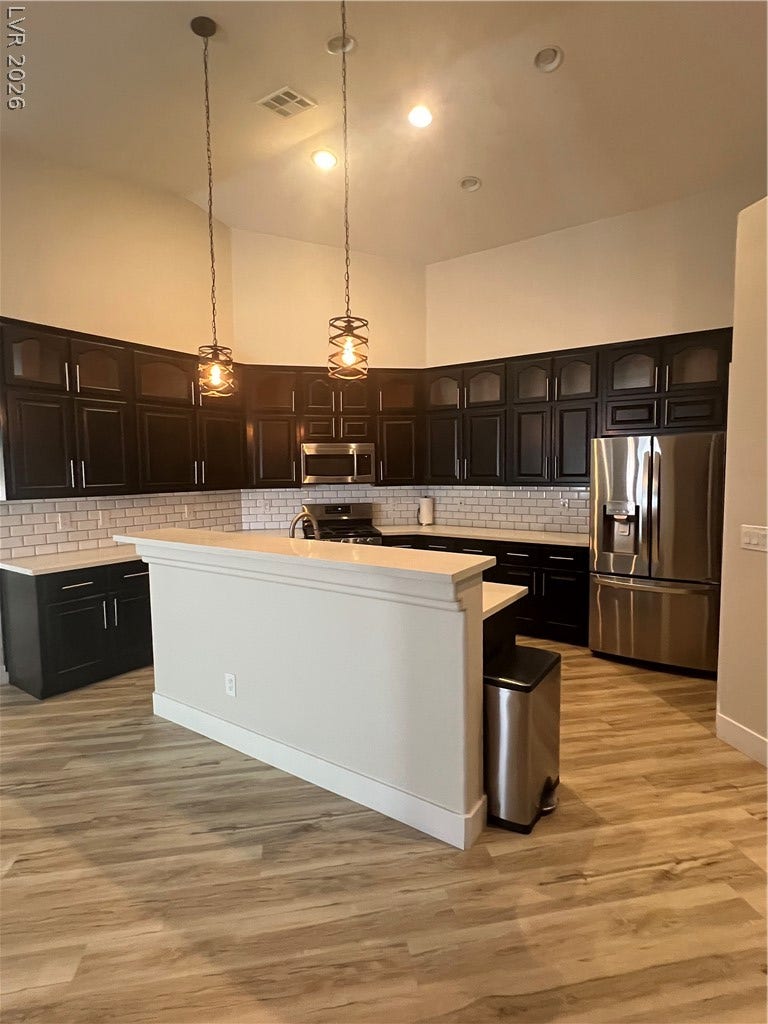 9621 Dancing Pond Way, Las Vegas, NV 89178 A well-appointed kitchen showcasing dark cabinetry, sleek appliances, and elegant pendant lighting.