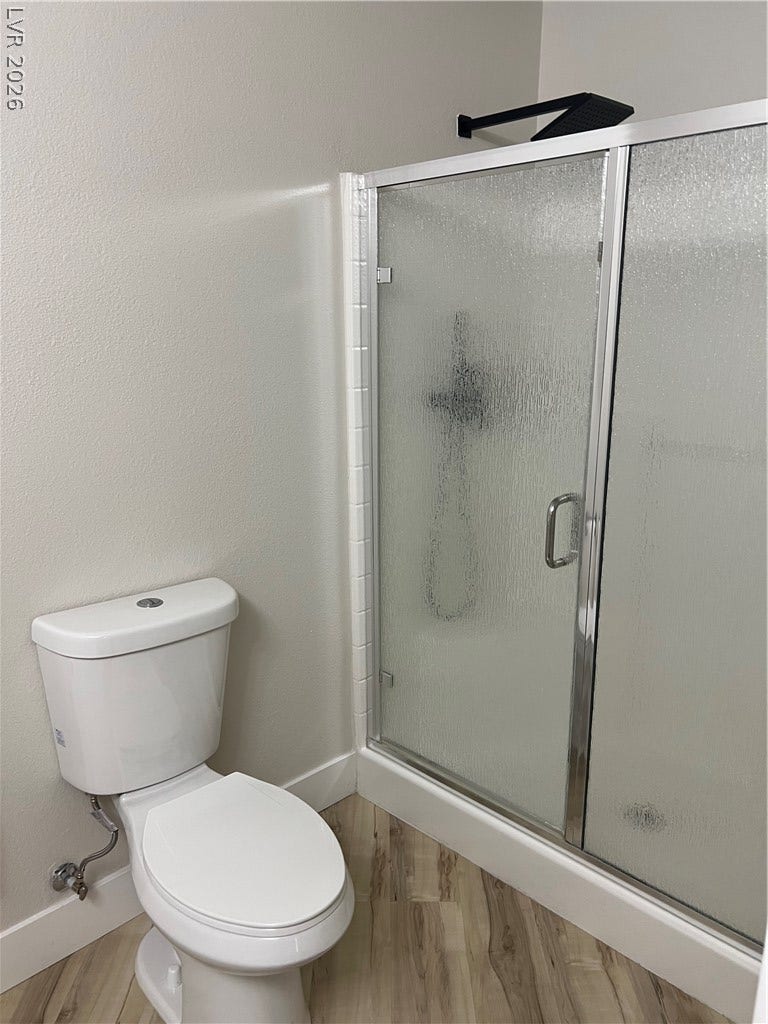 9621 Dancing Pond Way, Las Vegas, NV 89178 A well-appointed bathroom features a modern shower enclosure alongside a sleek, white toilet, complemented by stylish wood-look flooring.