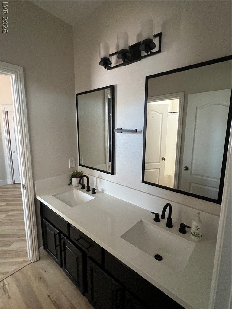 9621 Dancing Pond Way, Las Vegas, NV 89178 Double vanities with sleek black cabinetry and contrasting white countertops define this well-appointed bathroom.