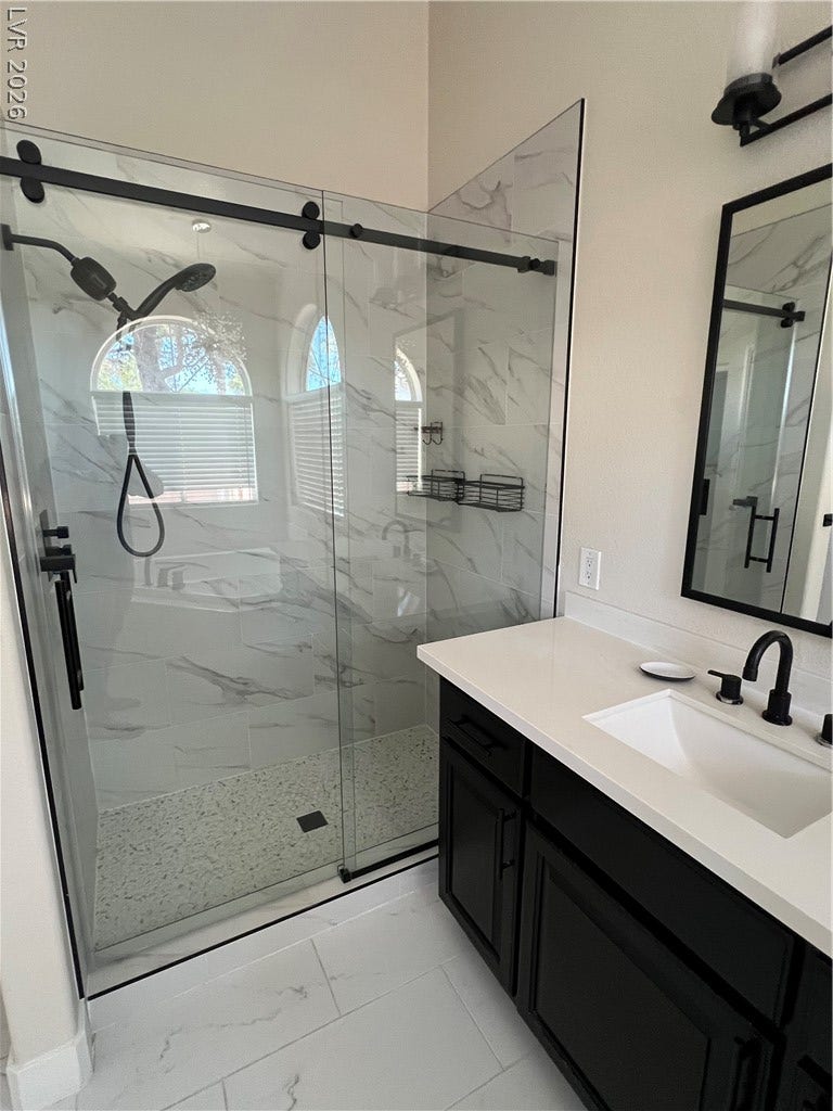 9621 Dancing Pond Way, Las Vegas, NV 89178 A well-appointed primary bathroom features a spacious walk-in shower with a sleek glass enclosure and a sophisticated vanity.