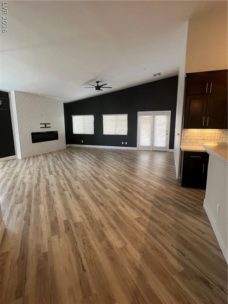 9621 Dancing Pond Way, Las Vegas, NV 89178 Long, flowing wood plank flooring extends into a well-appointed kitchen with rich dark cabinetry.