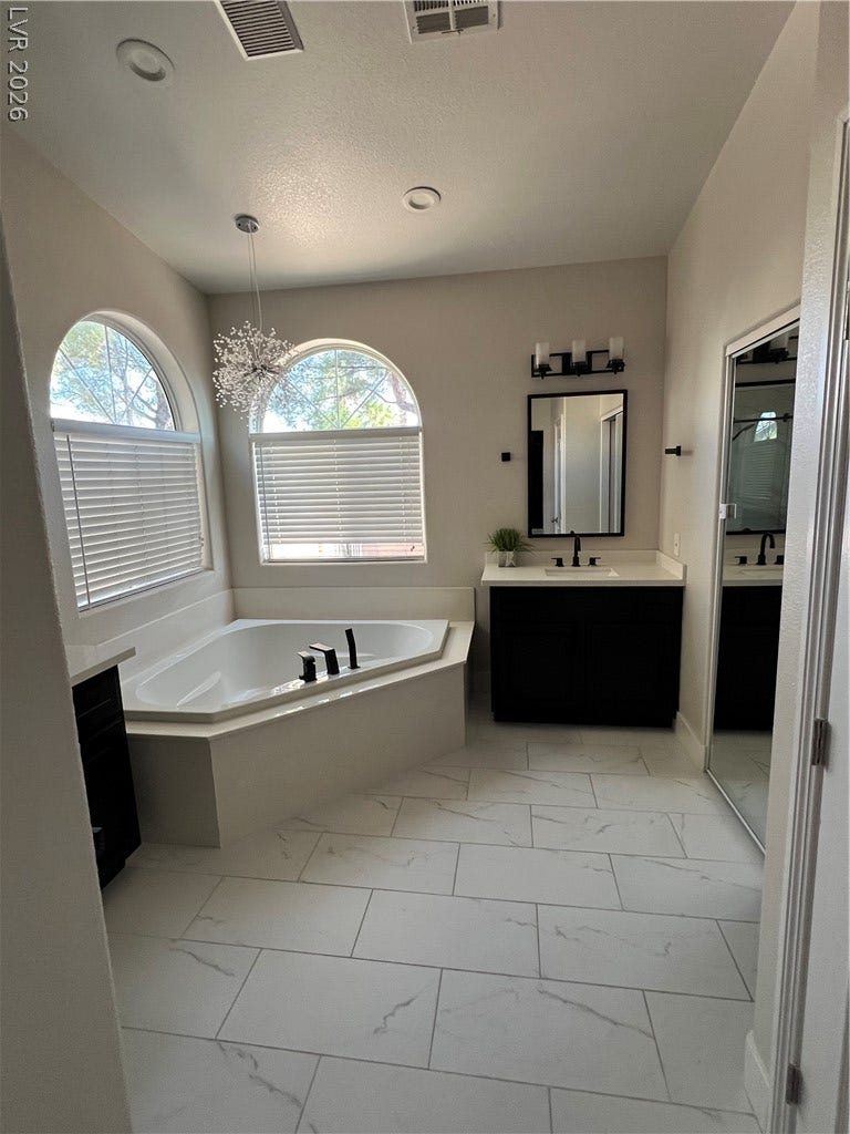 9621 Dancing Pond Way, Las Vegas, NV 89178 Relax in the deep soaking tub of this elegant bathroom featuring tall ceilings and arched windows.