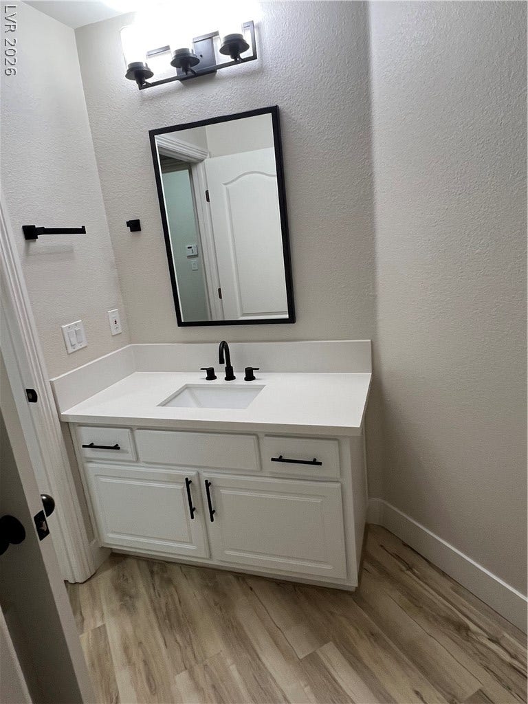 9621 Dancing Pond Way, Las Vegas, NV 89178 A well-appointed vanity area featuring a clean, white cabinet with ample storage, contrasted by dark fixtures and a broad mirror.