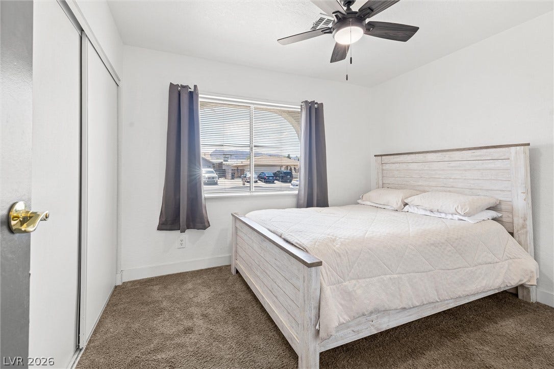525 Van Dornum Avenue, Henderson, NV 89011 Comfortable bedroom with ample natural light, featuring a modern ceiling fan and plush carpet flooring.