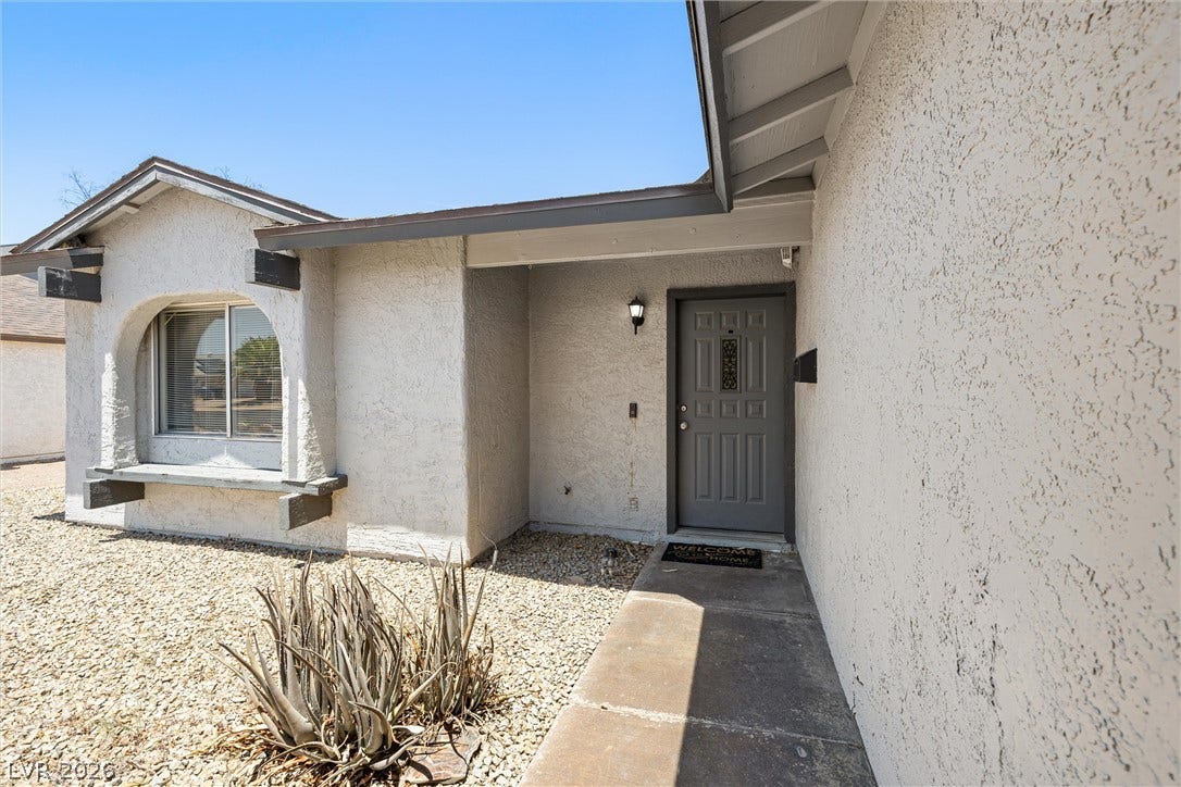525 Van Dornum Avenue, Henderson, NV 89011 An inviting front entry welcomes guests, framed by a window with a decorative archway and desert landscaping.