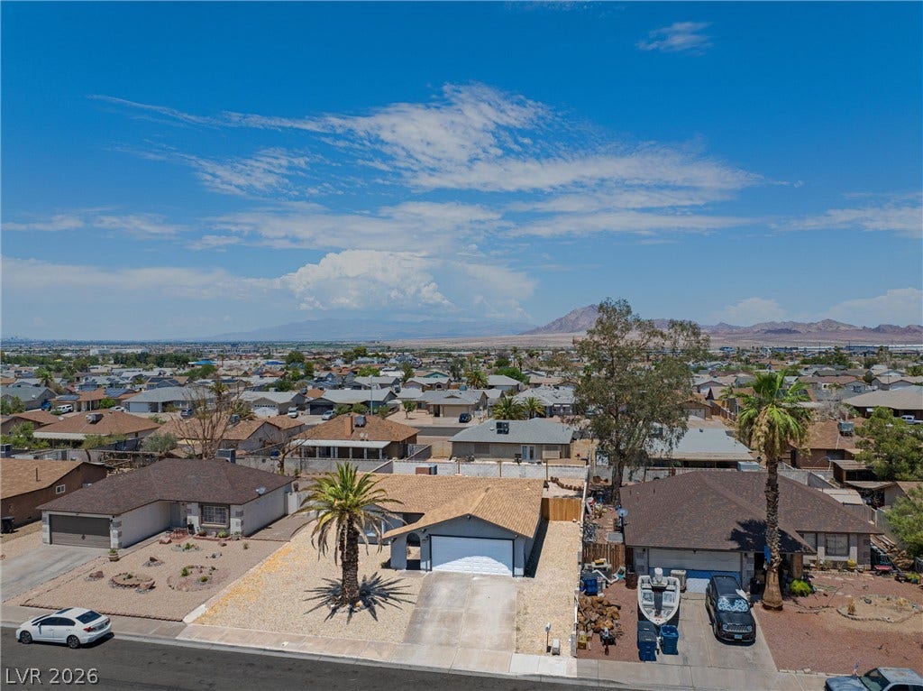 525 Van Dornum Avenue, Henderson, NV 89011 An aerial perspective reveals a desert neighborhood with individual homes, mountains in the distance, and a wide-open blue sky.