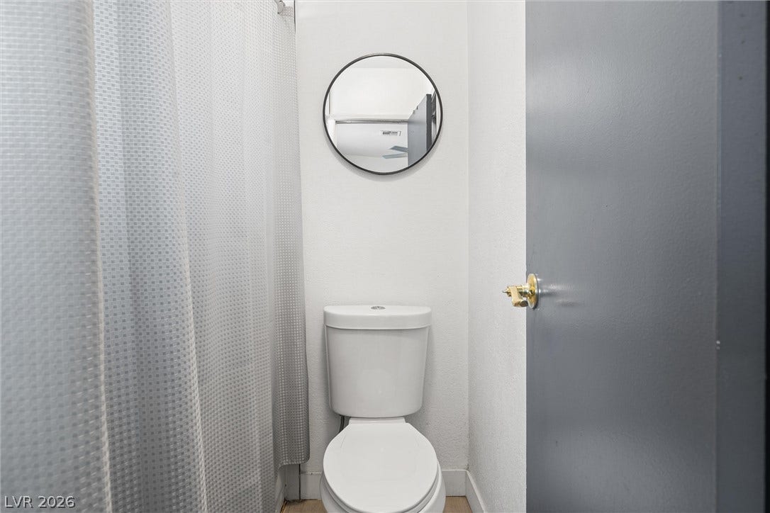 525 Van Dornum Avenue, Henderson, NV 89011 A compact and functional water closet with a classic toilet and a simple round mirror.