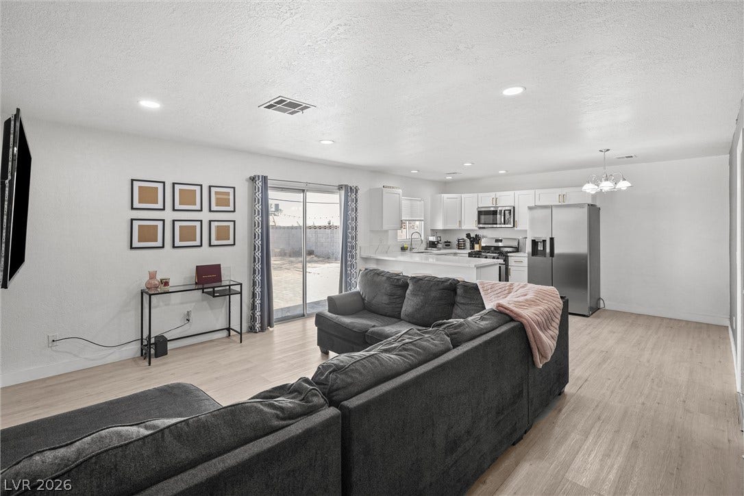 525 Van Dornum Avenue, Henderson, NV 89011 An open concept living area transitions fluidly into a modern kitchen, featuring sleek stainless steel appliances and ample counter space.