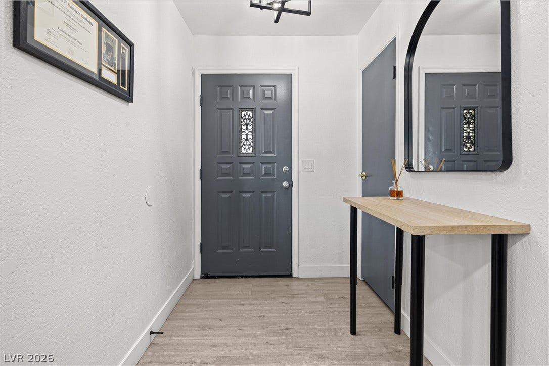 525 Van Dornum Avenue, Henderson, NV 89011 A welcoming entry features a stylish dark gray door with decorative glass, complemented by light wood-look flooring.