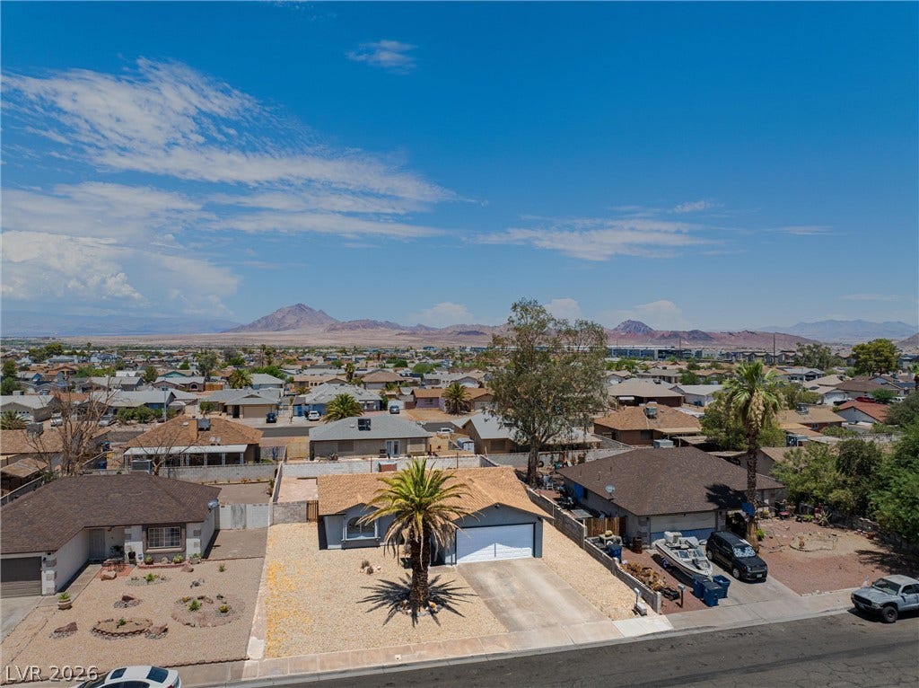 525 Van Dornum Avenue, Henderson, NV 89011 An aerial perspective reveals a charming desert home nestled within a community, set against a distant mountain range.