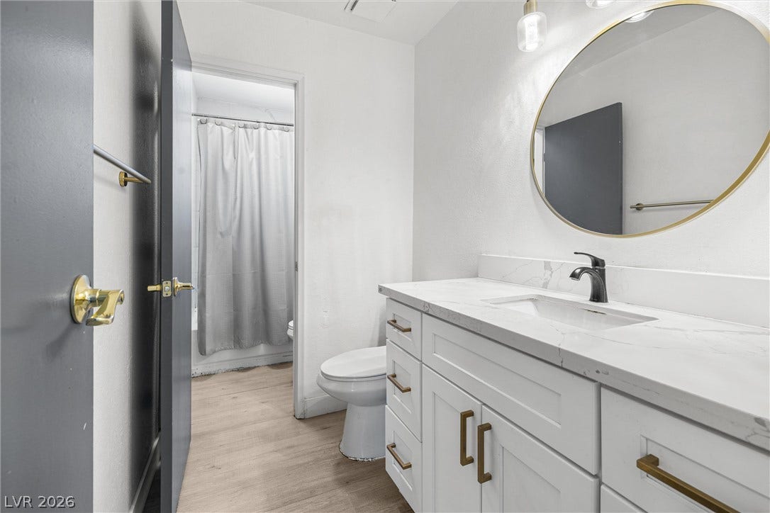 525 Van Dornum Avenue, Henderson, NV 89011 Modern bath with bright white vanity, sleek faucet, and circular mirror for a clean aesthetic.