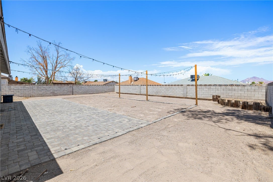 525 Van Dornum Avenue, Henderson, NV 89011 A spacious backyard with paver patio and string lights offers an inviting outdoor entertainment area.