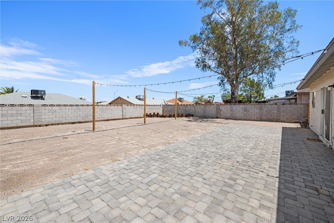 525 Van Dornum Avenue, Henderson, NV 89011 A spacious backyard features a paver patio and string lights, perfect for outdoor entertaining.