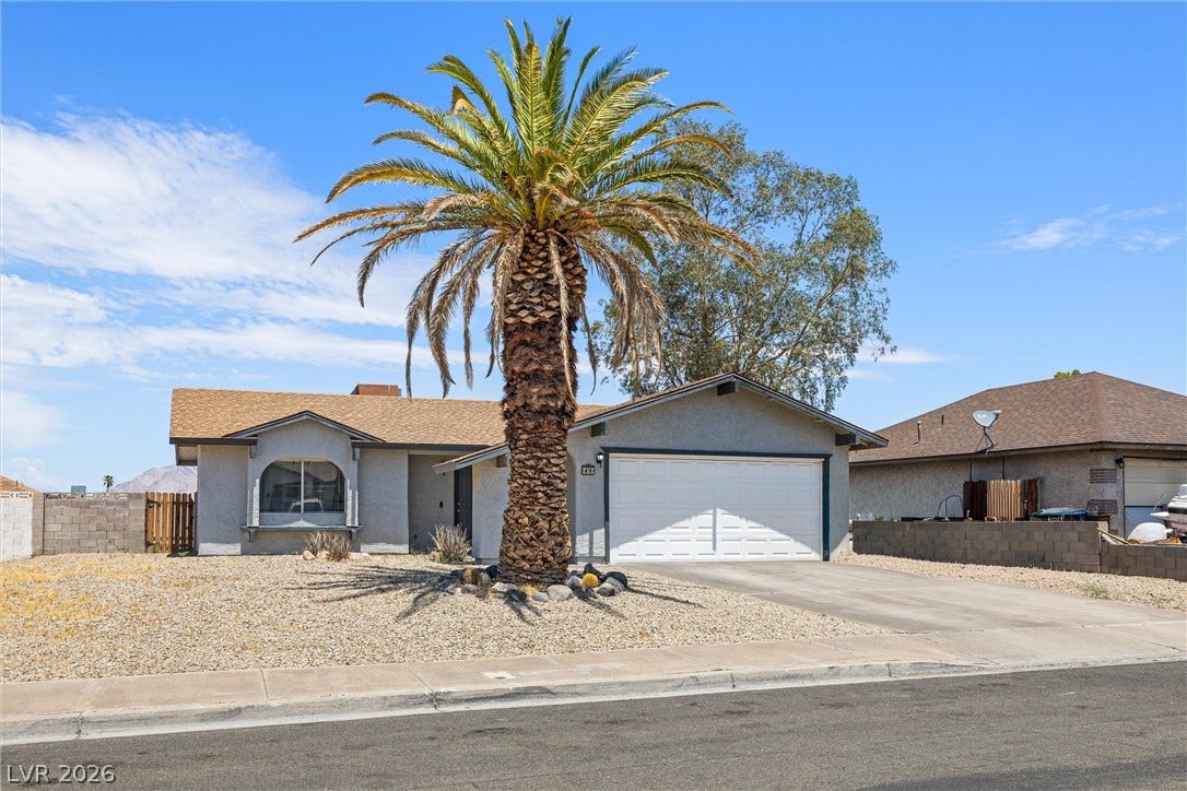 525 Van Dornum Avenue, Henderson, NV 89011 A desert-friendly landscape surrounds this charming stucco residence, featuring a prominent palm tree and an attached garage.