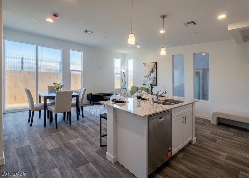 4926 Sweet Vesper Court, Las Vegas, NV 89108 An open-concept layout connects the kitchen, dining, and living areas seamlessly over wood-style flooring.