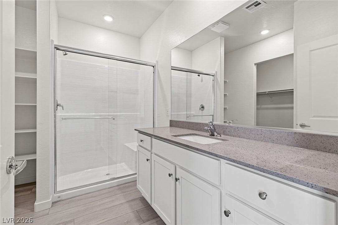 A well-appointed bathroom features a spacious shower, ample vanity space, and built-in shelving.