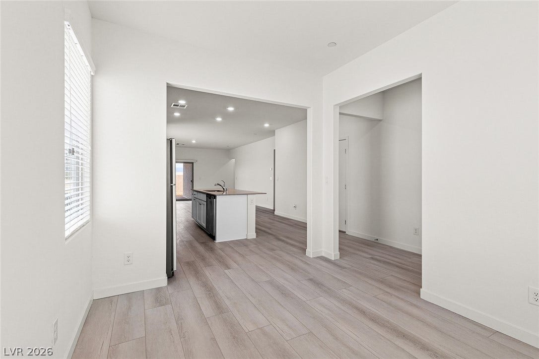 A well-lit, open-concept living space features wood flooring leading to a functional kitchen island.