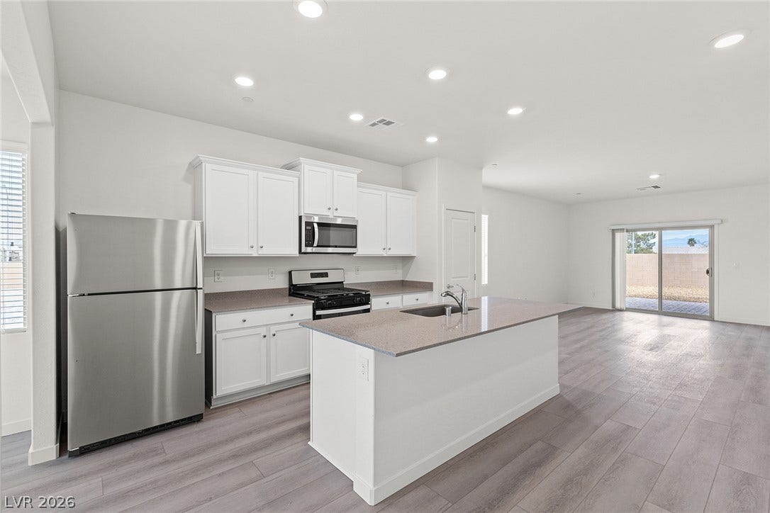 A well-appointed kitchen island anchors this open-concept living space, featuring contemporary cabinetry and seamless outdoor access.