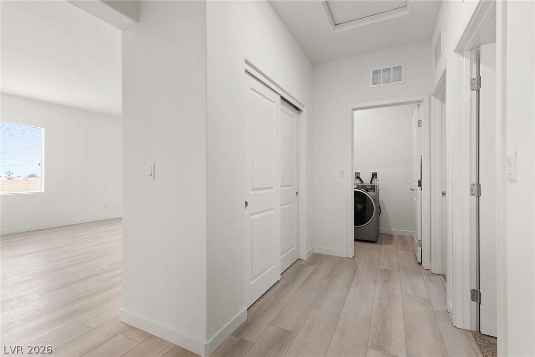 Functional laundry nook adjacent to a versatile room, boasting light wood-look flooring.