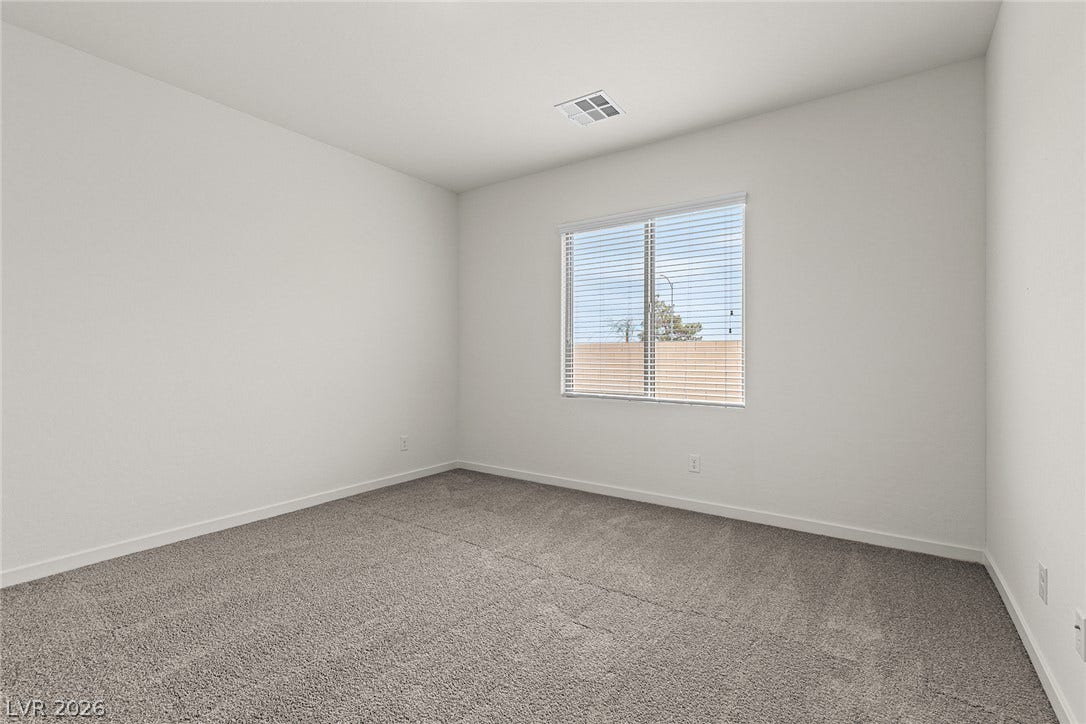 An inviting secondary bedroom offers soft carpeting and ample natural light through a generous window.