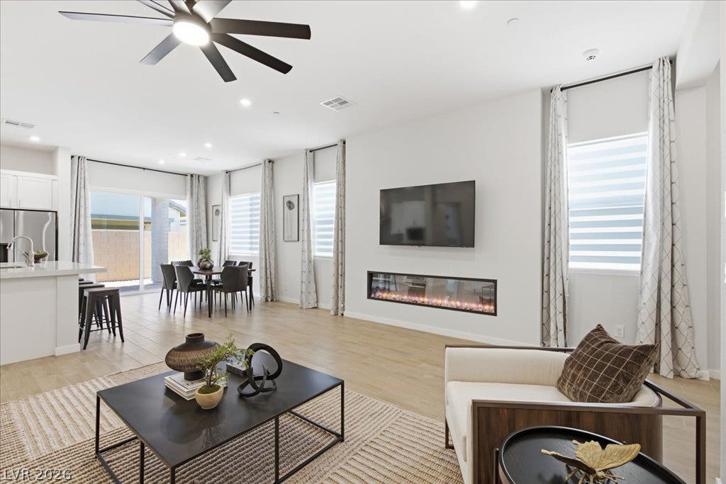 847 Eaton Falls Street, Henderson, NV 89011 An open-concept living area offers an electric fireplace, light wood flooring, and plentiful natural light.