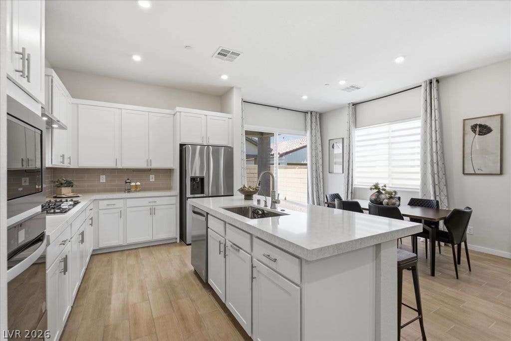 847 Eaton Falls Street, Henderson, NV 89011 A well-lit kitchen with sleek white cabinetry, a large center island, and an open layout seamlessly connecting to the dining area.