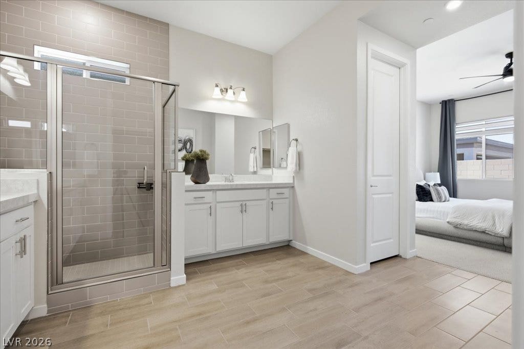847 Eaton Falls Street, Henderson, NV 89011 A well-appointed bathroom offers a glass-enclosed shower and a dual-vanity setup, connecting seamlessly to a bedroom.