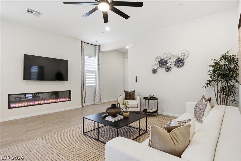 847 Eaton Falls Street, Henderson, NV 89011 A streamlined living area showcases a contemporary fireplace, sleek ceiling fan, and light-toned flooring.