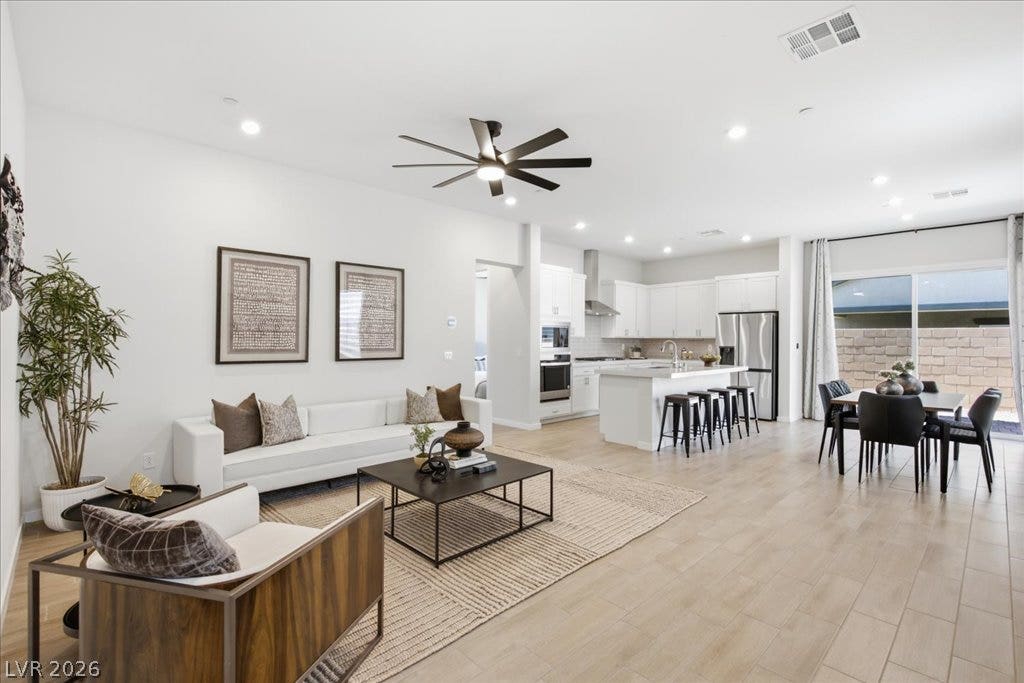 847 Eaton Falls Street, Henderson, NV 89011 An open-concept living space features modern lighting, sleek flooring, and seamless transitions to a contemporary kitchen and dining area.