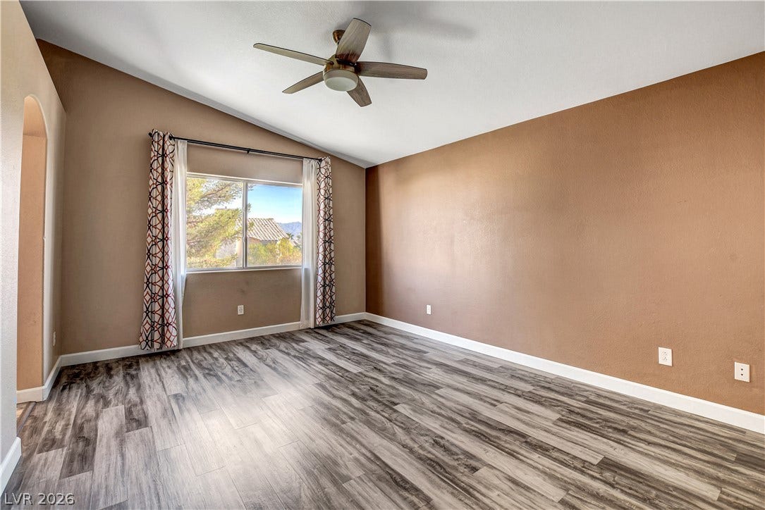 8308 Raphael Court, Las Vegas, NV 89129 A generous room features vaulted ceilings, rich wood-look flooring, and a large window framing distant mountain views.