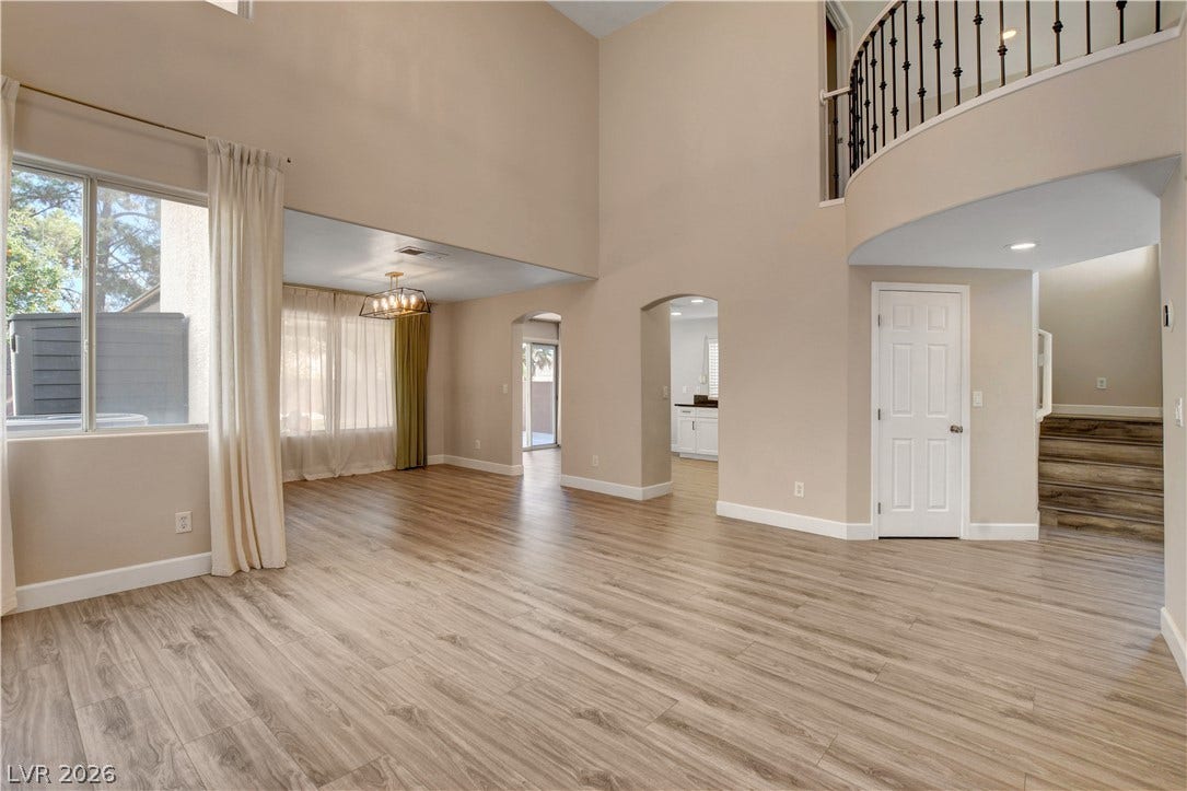 8308 Raphael Court, Las Vegas, NV 89129 A spacious living area with soaring ceilings and light wood-look flooring, offering an inviting atmosphere.