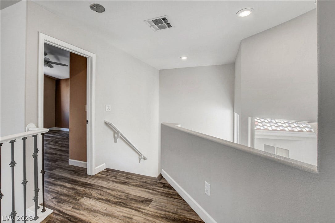 8308 Raphael Court, Las Vegas, NV 89129 Rich wood flooring guides you through this airy upper-level landing, featuring a white baluster and sleek wall railing.