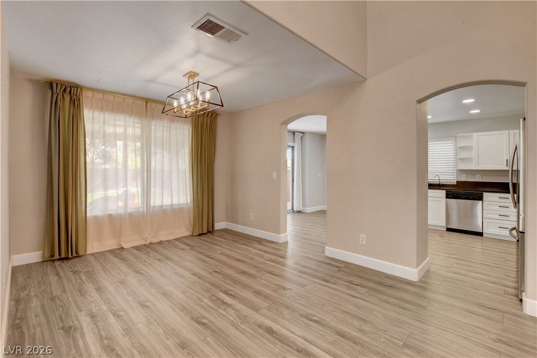 8308 Raphael Court, Las Vegas, NV 89129 Luminous dining area with sleek wood flooring and a contemporary chandelier, leading into an open kitchen.