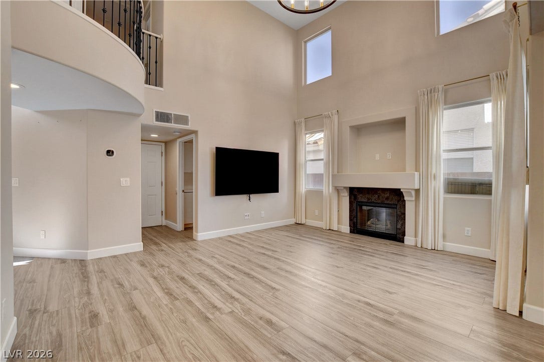 8308 Raphael Court, Las Vegas, NV 89129 Grand living room features soaring ceilings, natural light, a gas fireplace, and an elegant second-story balcony overlook.