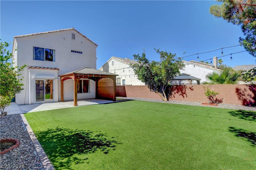 8308 Raphael Court, Las Vegas, NV 89129 A spacious backyard retreat features a covered patio and verdant artificial turf, perfect for outdoor living.