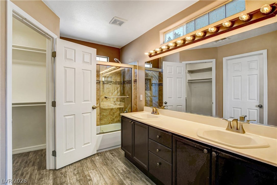 8308 Raphael Court, Las Vegas, NV 89129 A well-lit bathroom features a spacious vanity with dual sinks, shower, and generous storage options.