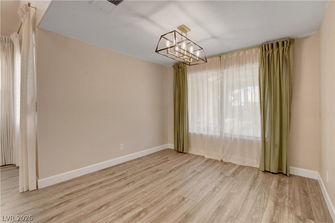 8308 Raphael Court, Las Vegas, NV 89129 A well-lit room features new hardwood-style flooring and a modern geometric light fixture.