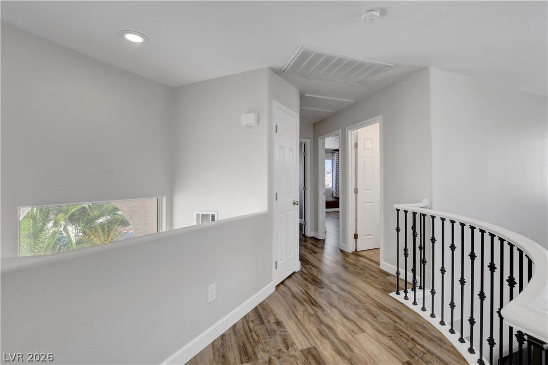 8308 Raphael Court, Las Vegas, NV 89129 A graceful curved staircase leads to a well-lit upper landing, featuring durable flooring and multiple access points to additional rooms.
