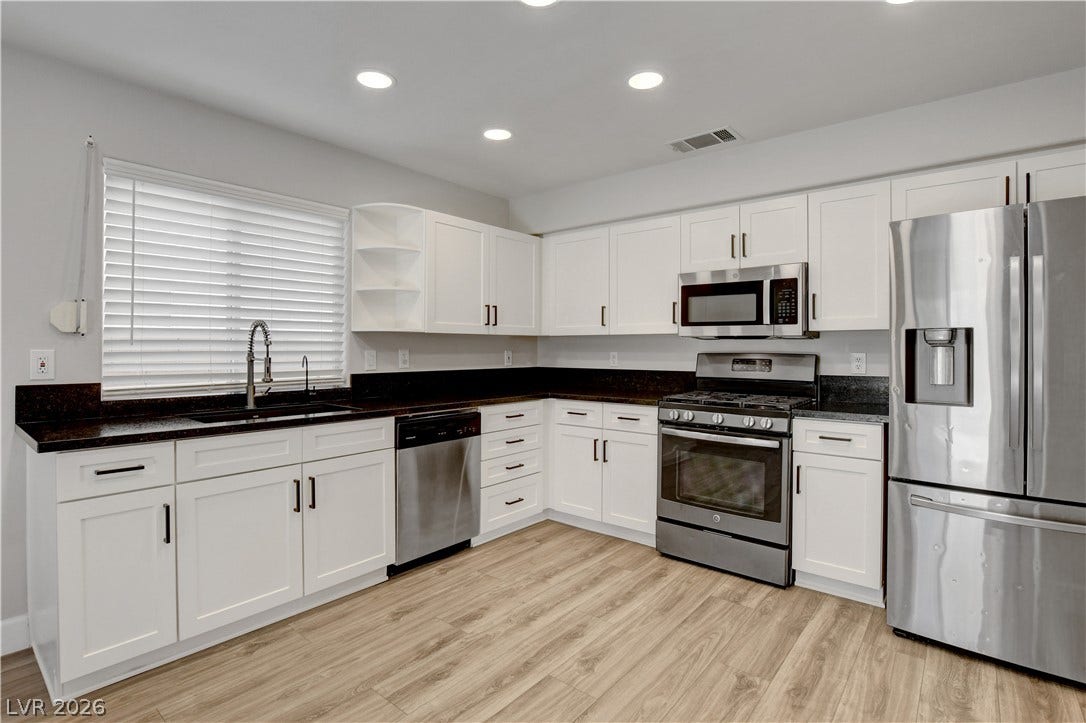 8308 Raphael Court, Las Vegas, NV 89129 A well-appointed kitchen features dark granite countertops complementing crisp white cabinetry and new stainless steel appliances.