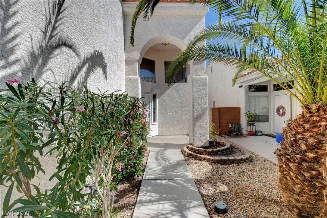 8308 Raphael Court, Las Vegas, NV 89129 Enter through a welcoming arched entryway, framed by vibrant green landscaping.